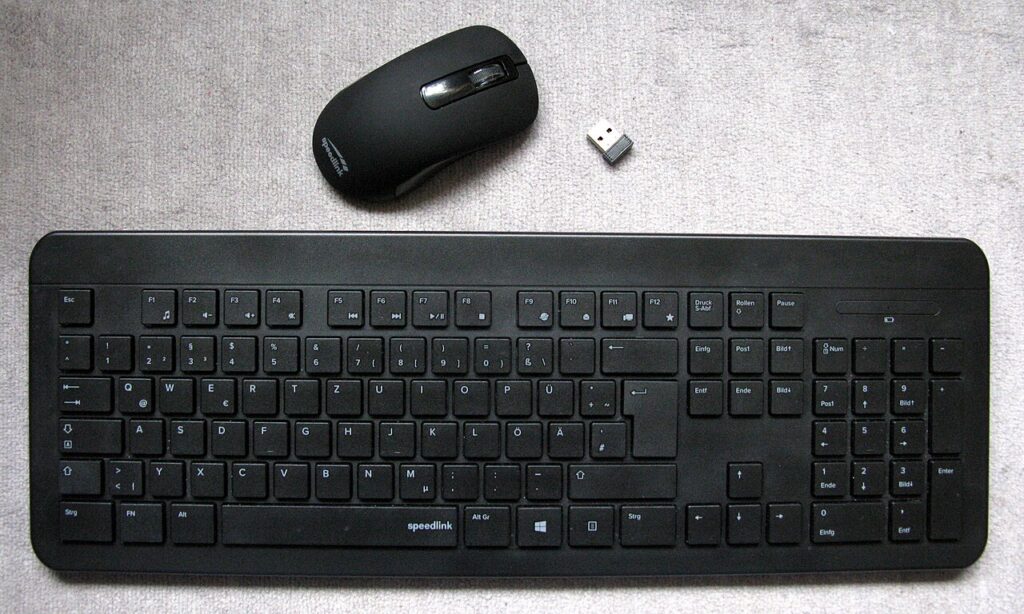 밝은 천 위에 놓인 검은색 무선 키보드와 마우스, 작은 USB 수신기
