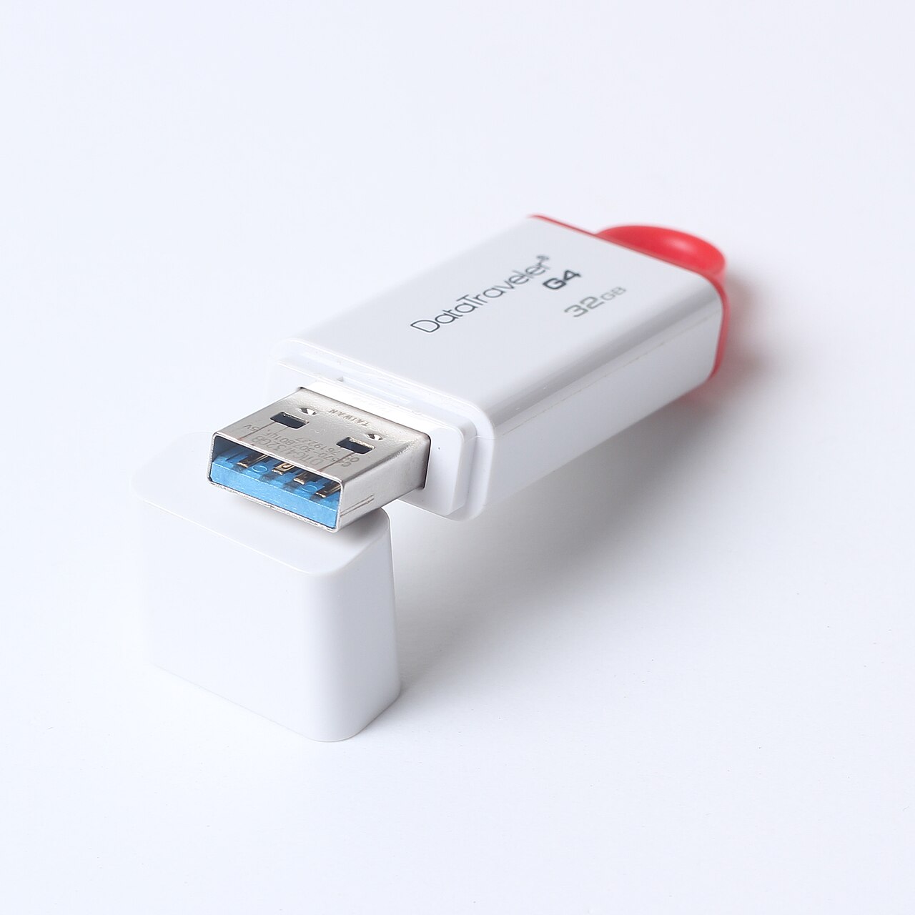 흰색 본체에 빨간 고리가 달린 32GB USB 메모리와 분리된 보호 캡